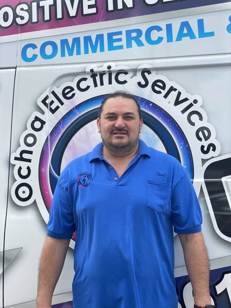 Ochoa Electric Services official van with contact details and "45-hour service" wording on it, with a man with blue tshirt standing beside the van